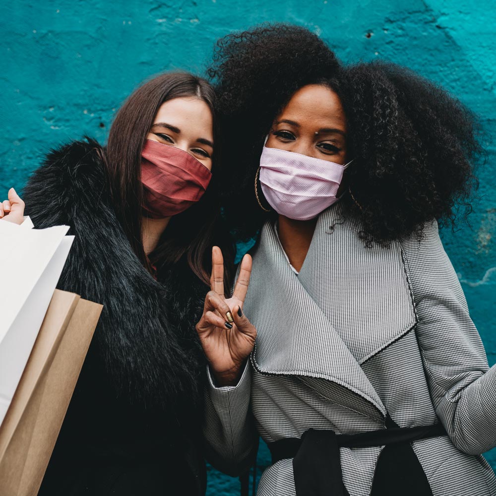 Two girls smiling wearing face masks