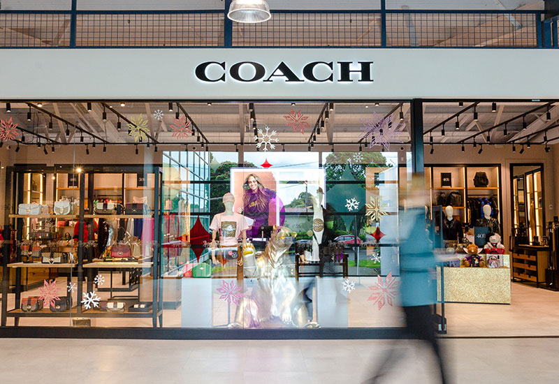 Photo of the Coach store at Dress Smart, with a person walking past in the foreground