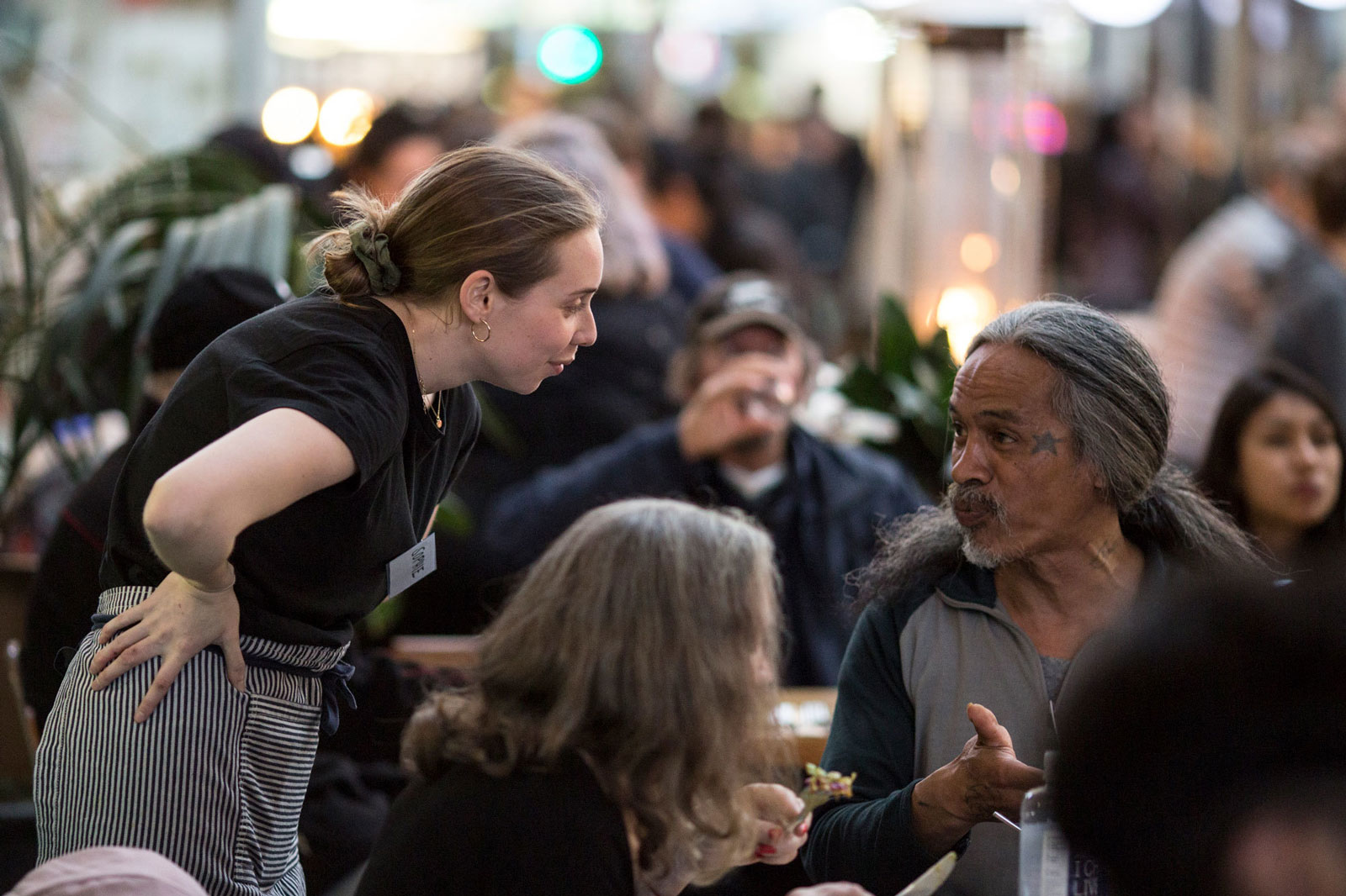 Photo of a volunteer chatting with a customer at an Everybody Eats meal